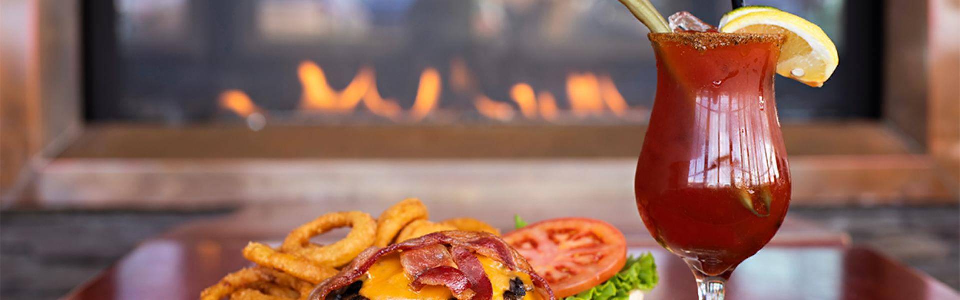 Open face burger served with onion rings and a garnished caesar