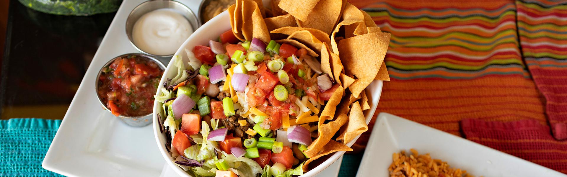 Fresh Mexican salad bowl served with salsa and sour cream