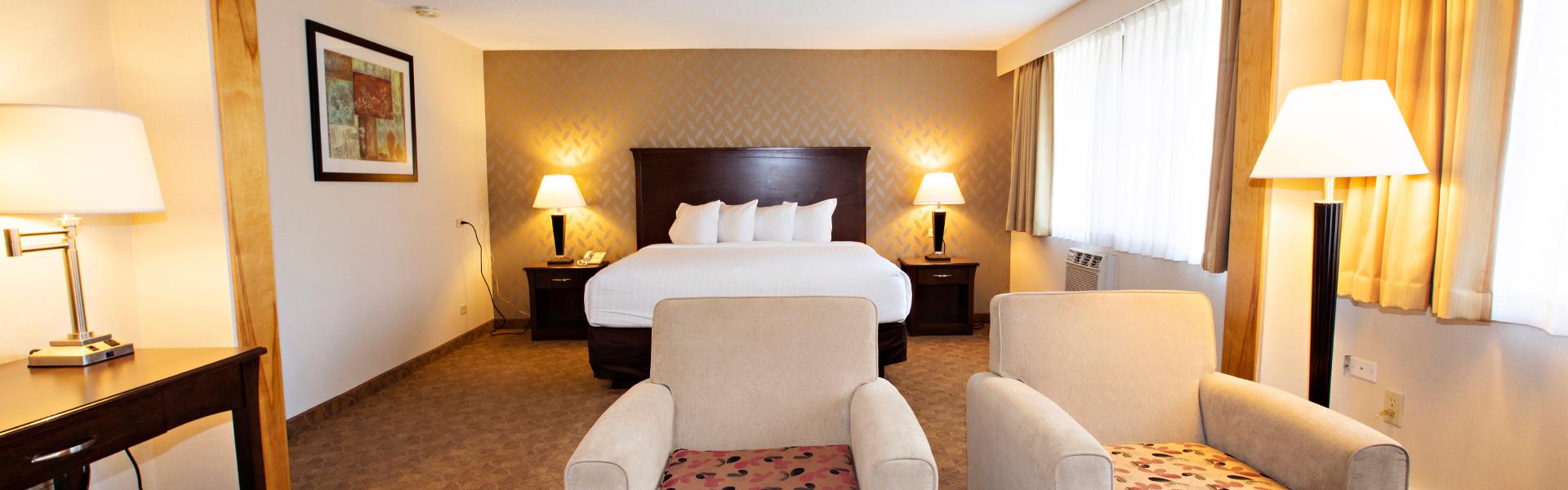 A spacious and well lit hotel room with comfortable chairs