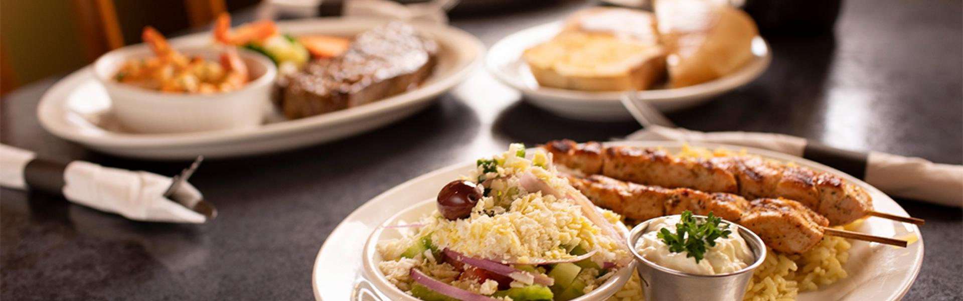 Plate serving Lamb chops with hummus, rice, pita bread