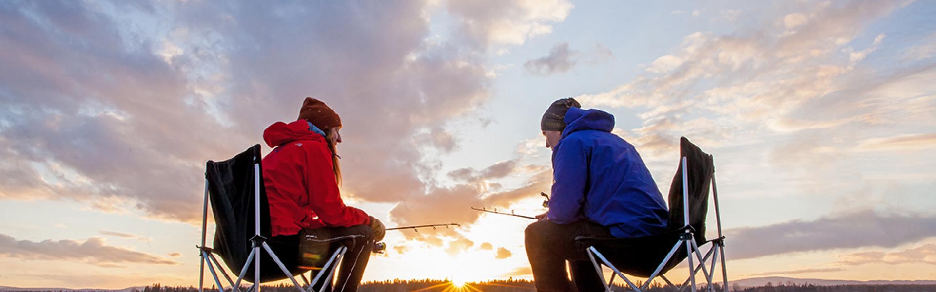 A couple ice-fishing on Dragon Lake during a beautiful sunset