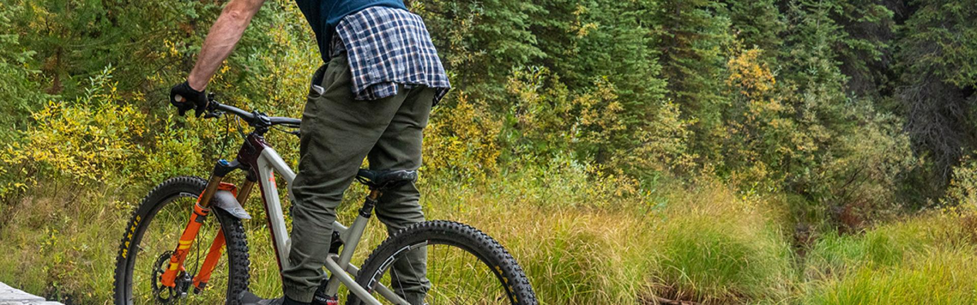 Man mountain biking over a narrow wooden bridge