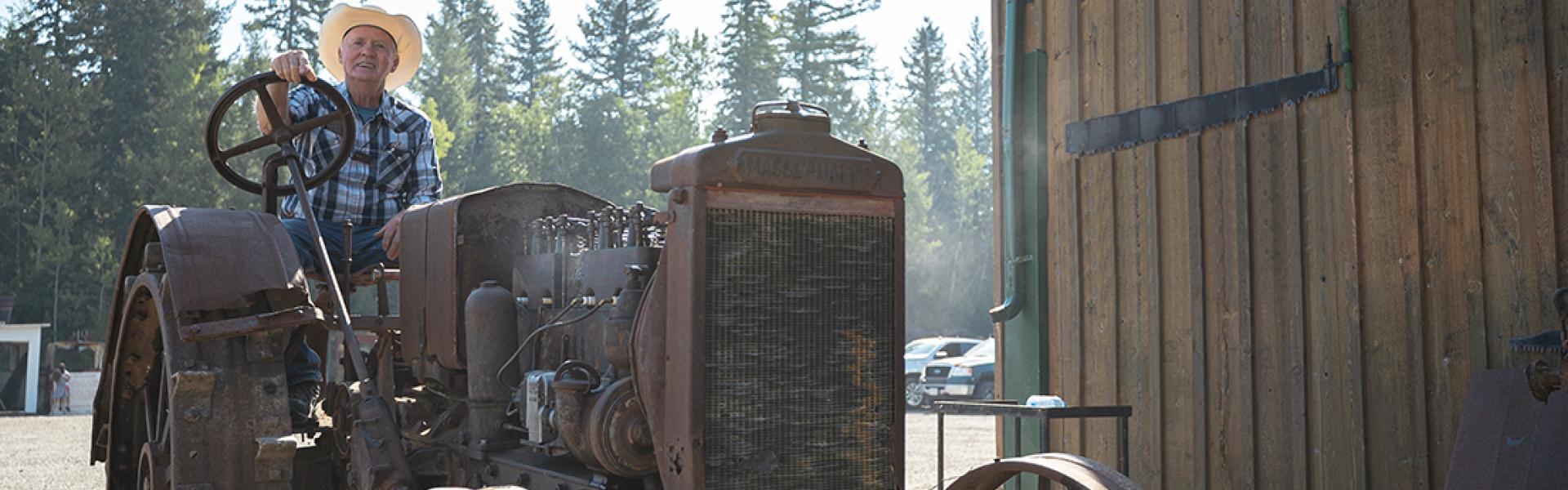 Gentleman in a cowboy hat sitting on an antique tractor 
