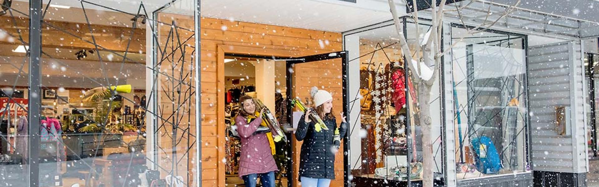 Two women walking out of Rocky Peak Adventure Gear with skis