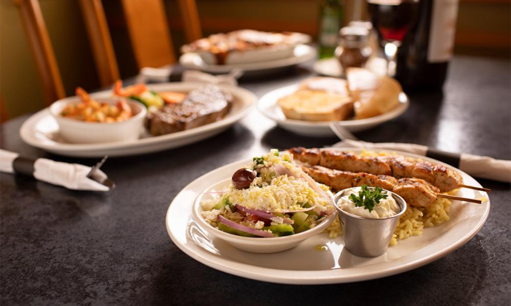 Plate serving Lamb chops with hummus, rice, pita bread