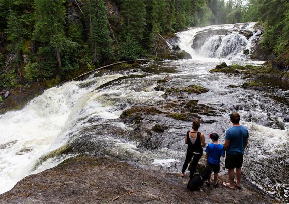 Family standing along Beavermouth Creek observing the waterfalls