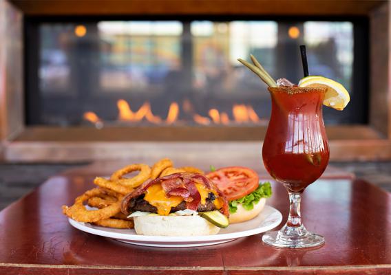 Open face burger served with onion rings and a garnished caesar