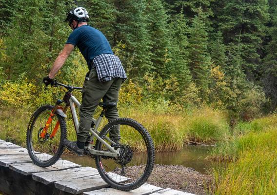 Man mountain biking over a narrow wooden bridge