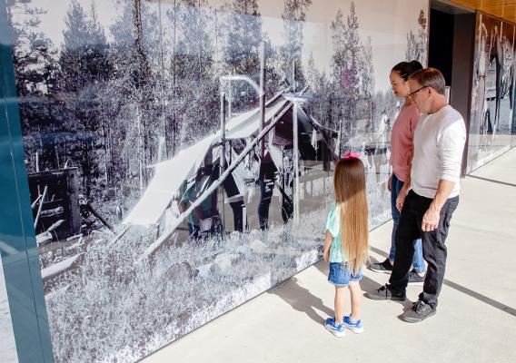 Family observing historic photos on the outside walls of the Quesnel Museum